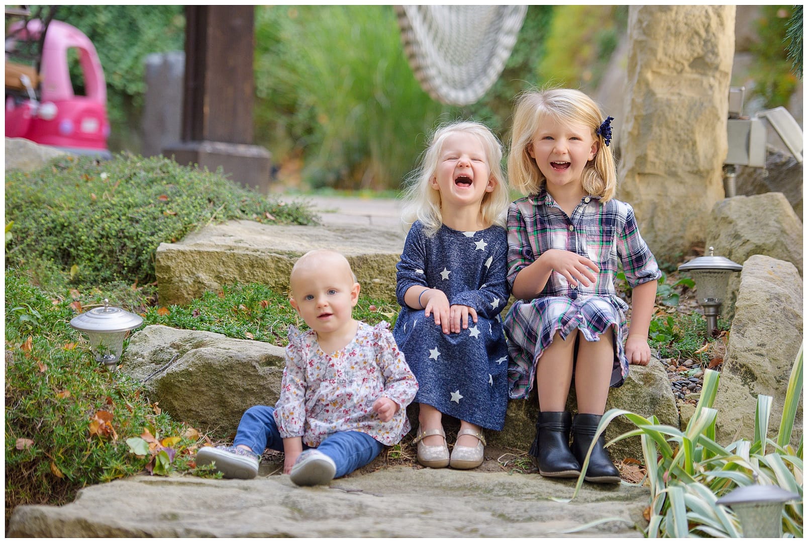 Three sisters laugh on steps in their yard. Photo by Tiffany Hix Photography.