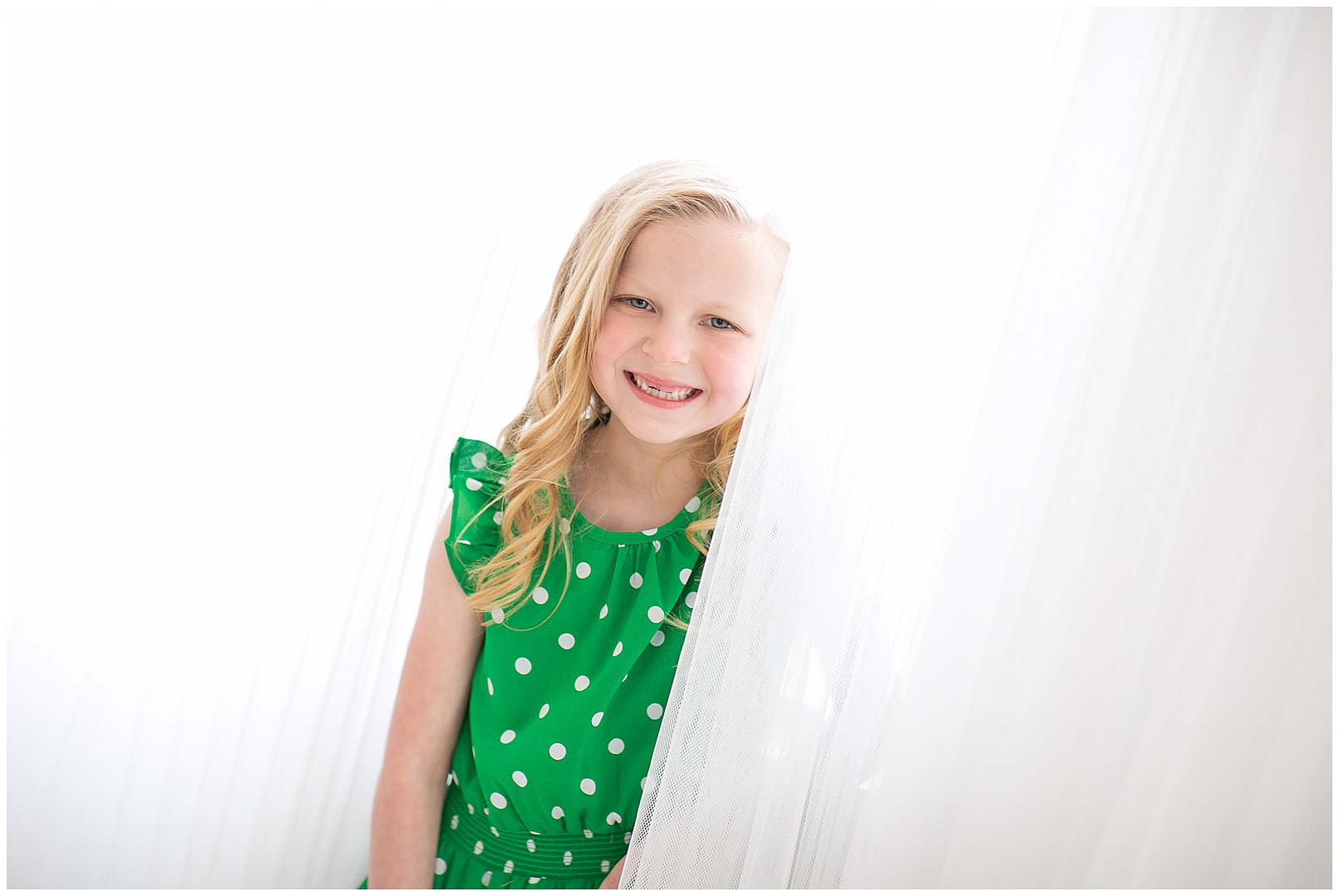 Girl smiles behind curtain. Photos by Tiffany Hix Photography.