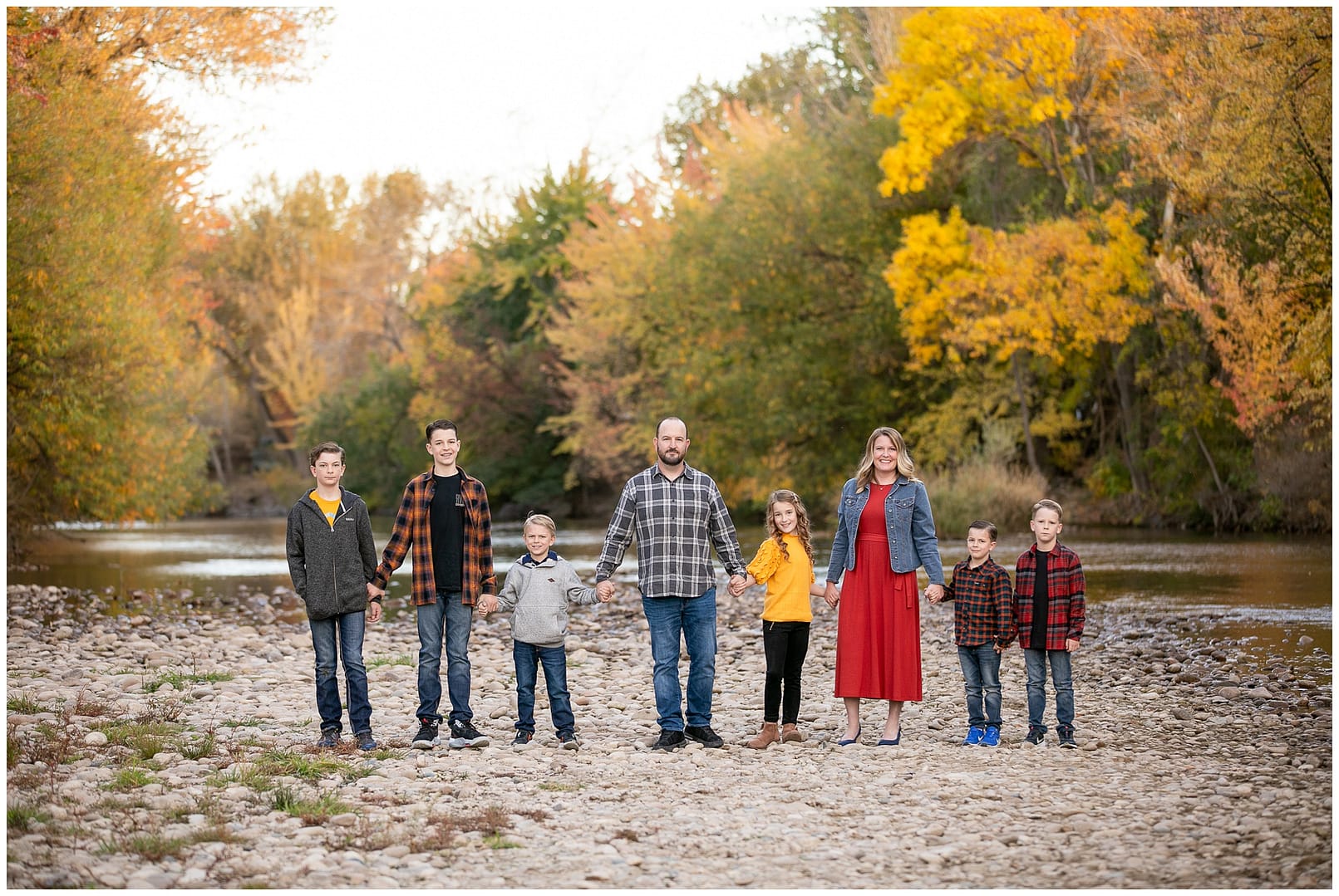 Boise family of eight holds hands in front of Boise River. Photos by Tiffany Hix Photography.
