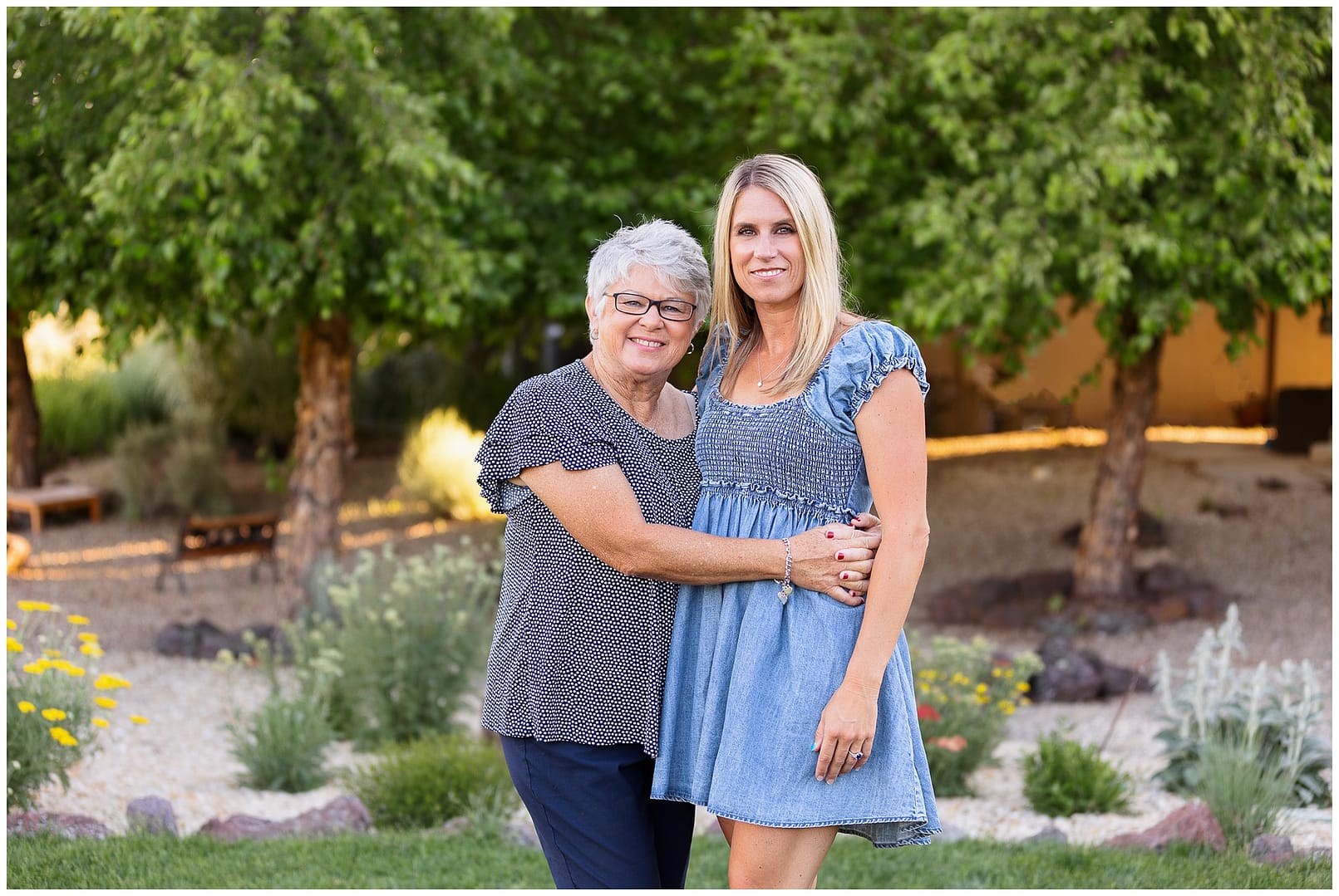 Mom & older daughter stand in yard smiling. Photo by Tiffany Hix Photography.