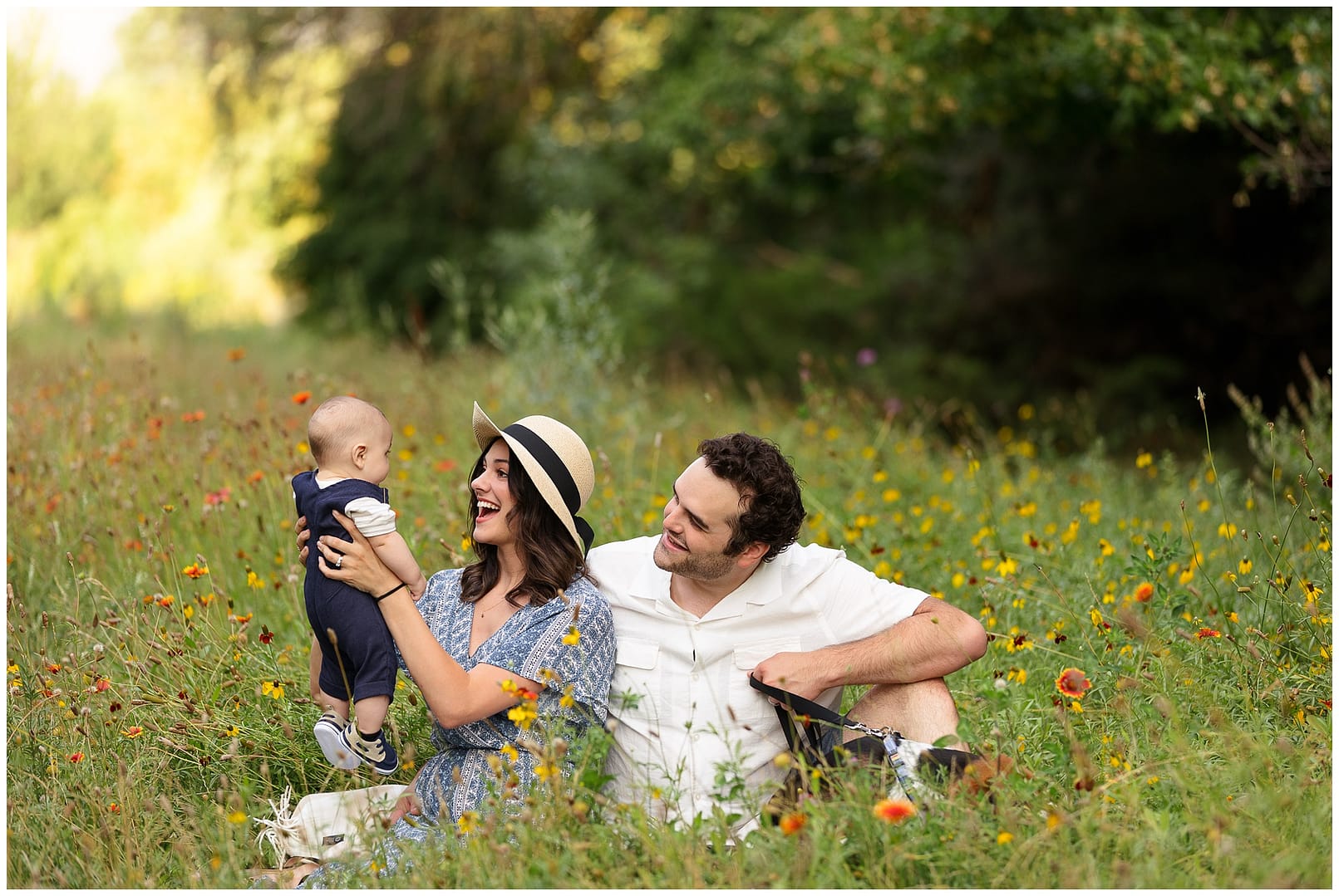 Parents smile at baby during natural family photos in a wildflower field. Photo by Tiffany Hix Photography.