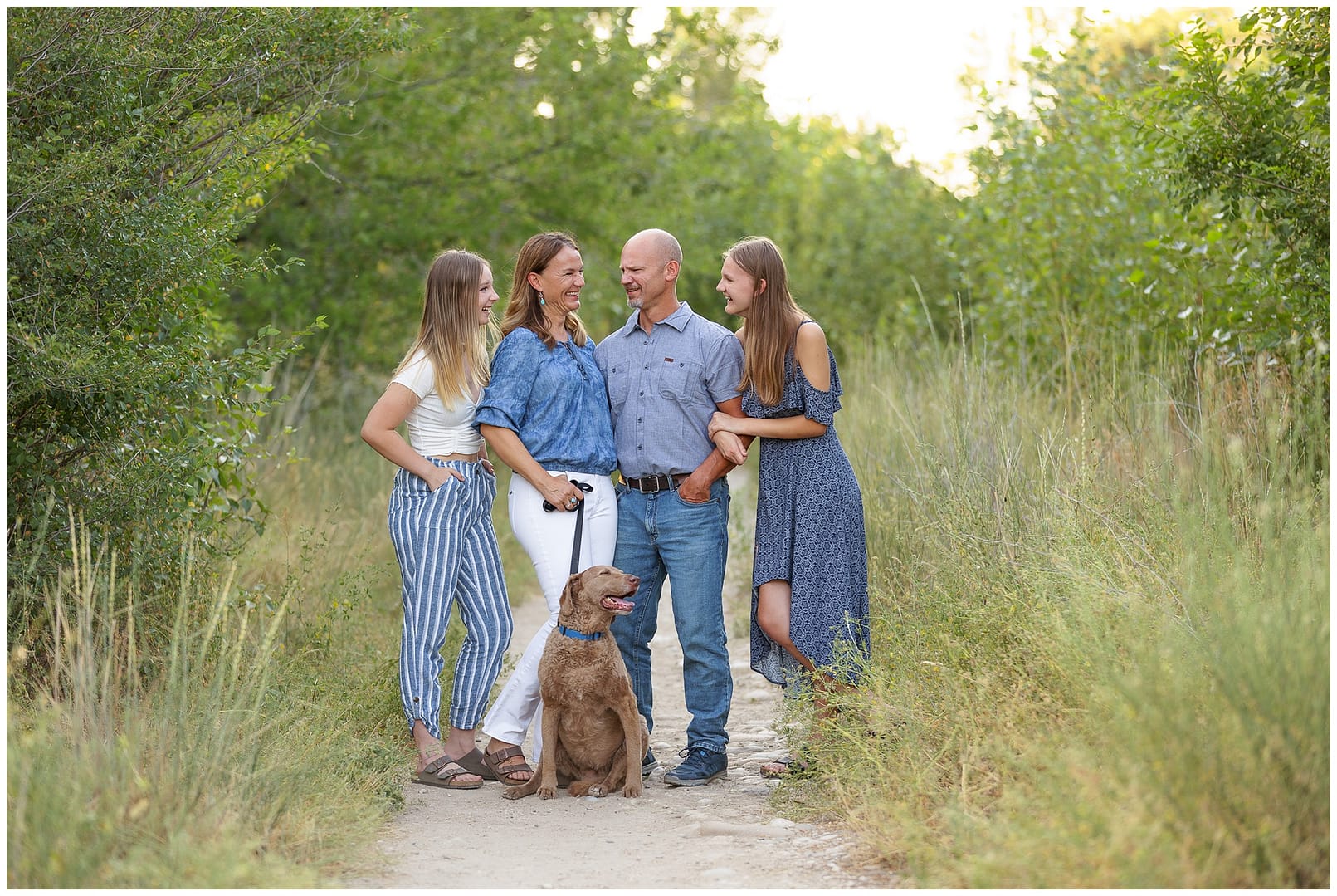 Family of four laughs with one another during family session on the Boise greenbelt. Photo by Tiffany Hix Photography.