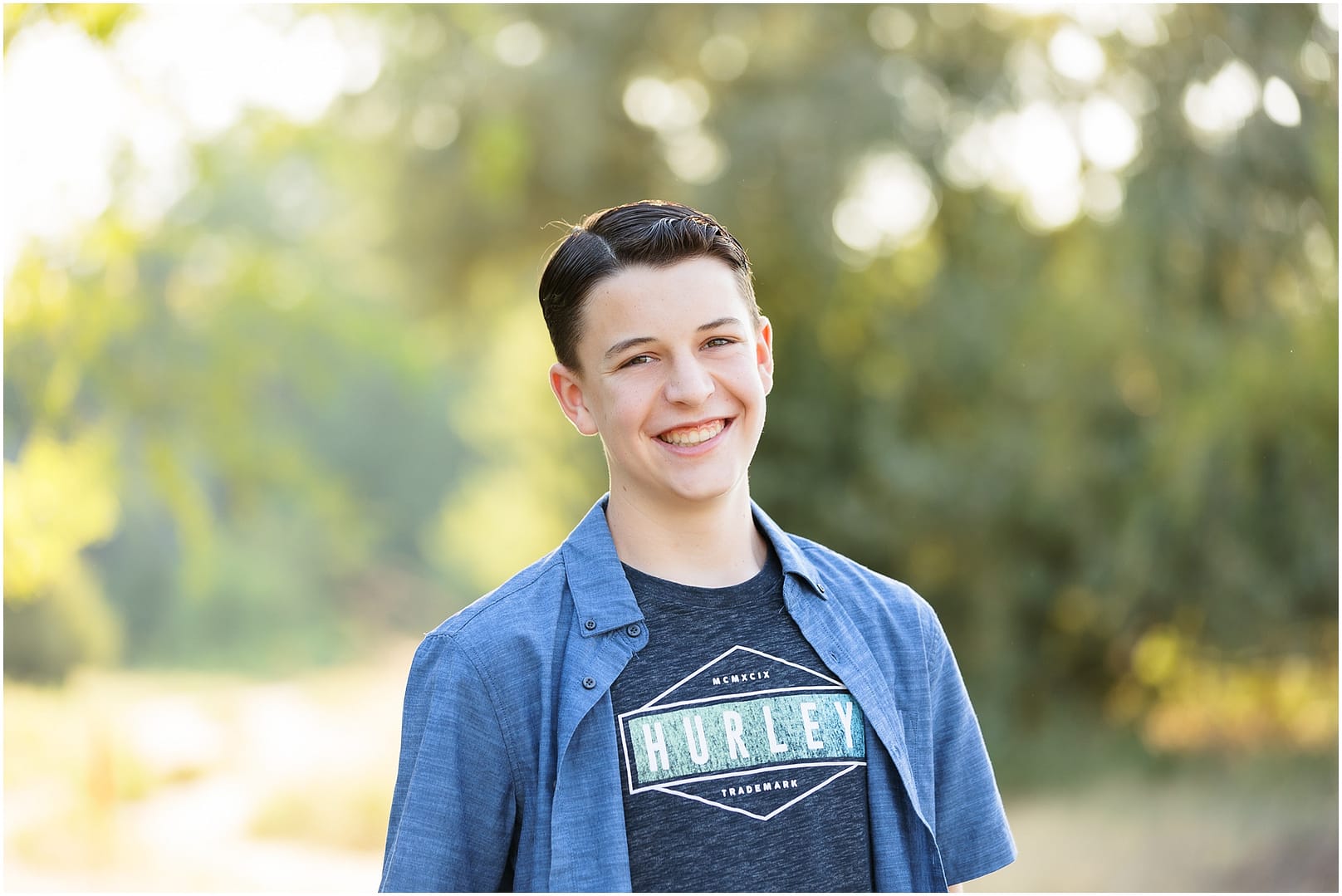Boy smiles in blue button up shirt during Boise teen boy portrait session. Photo by Tiffany Hix Photography.