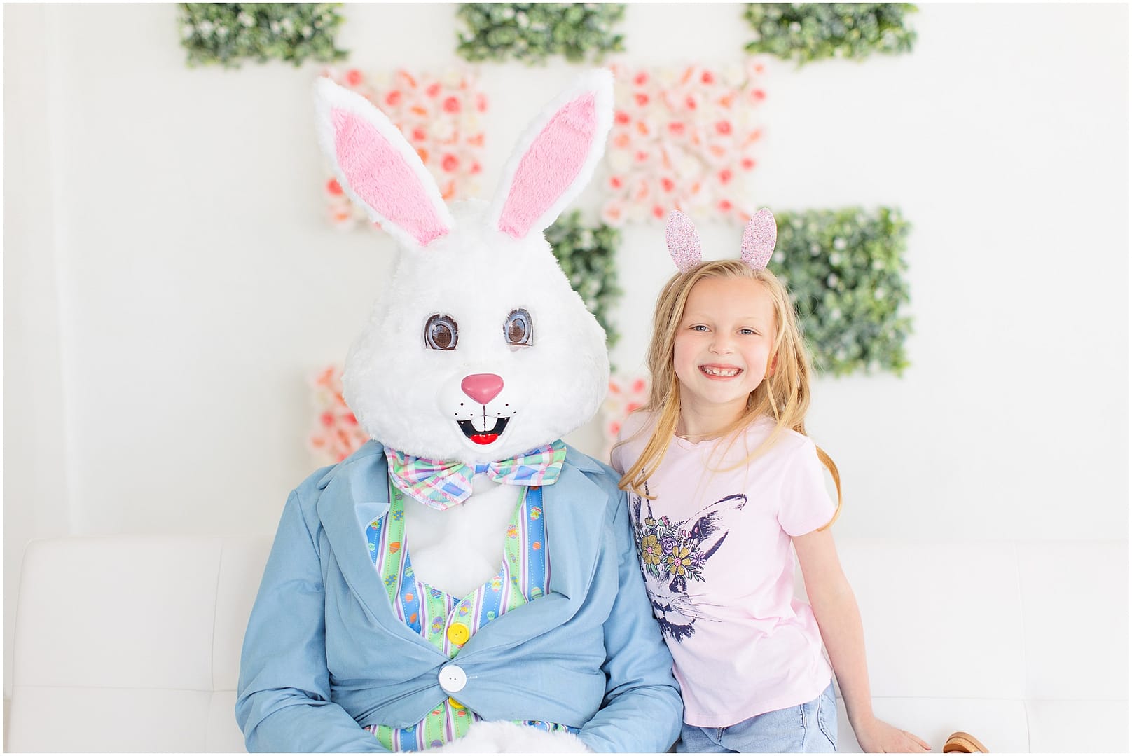 Young girl smiles while sitting next to the Easter Bunny. Photo by Tiffany Hix Photography.