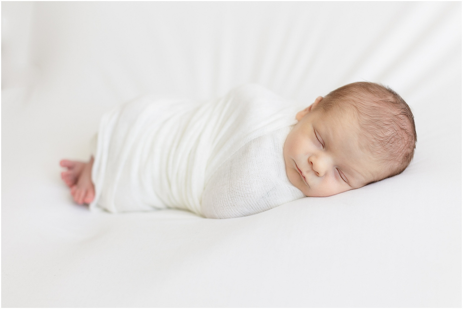 Newborn baby boy wrapped in white swaddle. Photo by Tiffany Hix Photography.
