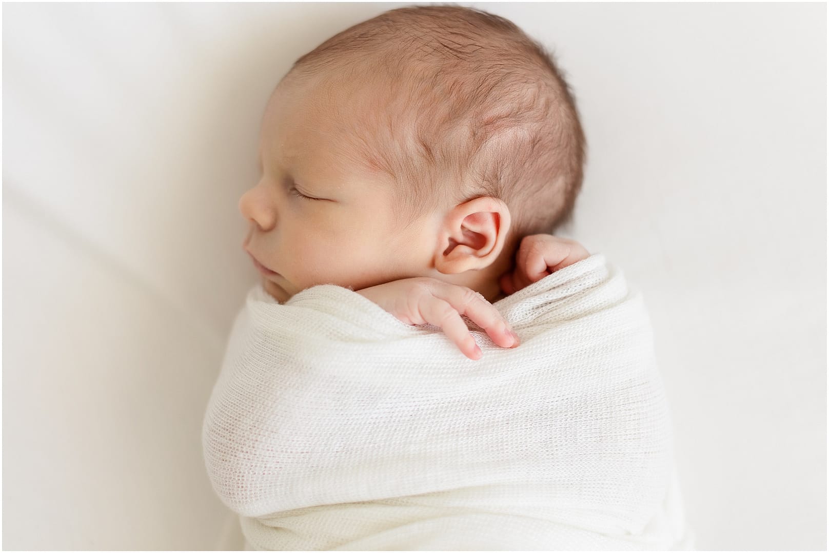 Side profile of newborn baby boy in swaddle. Photo by Tiffany Hix Photography.