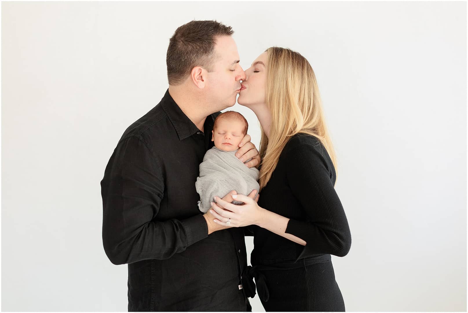 Mom and Dad go in for a kiss during newborn session. Photo by Tiffany Hix Photography.