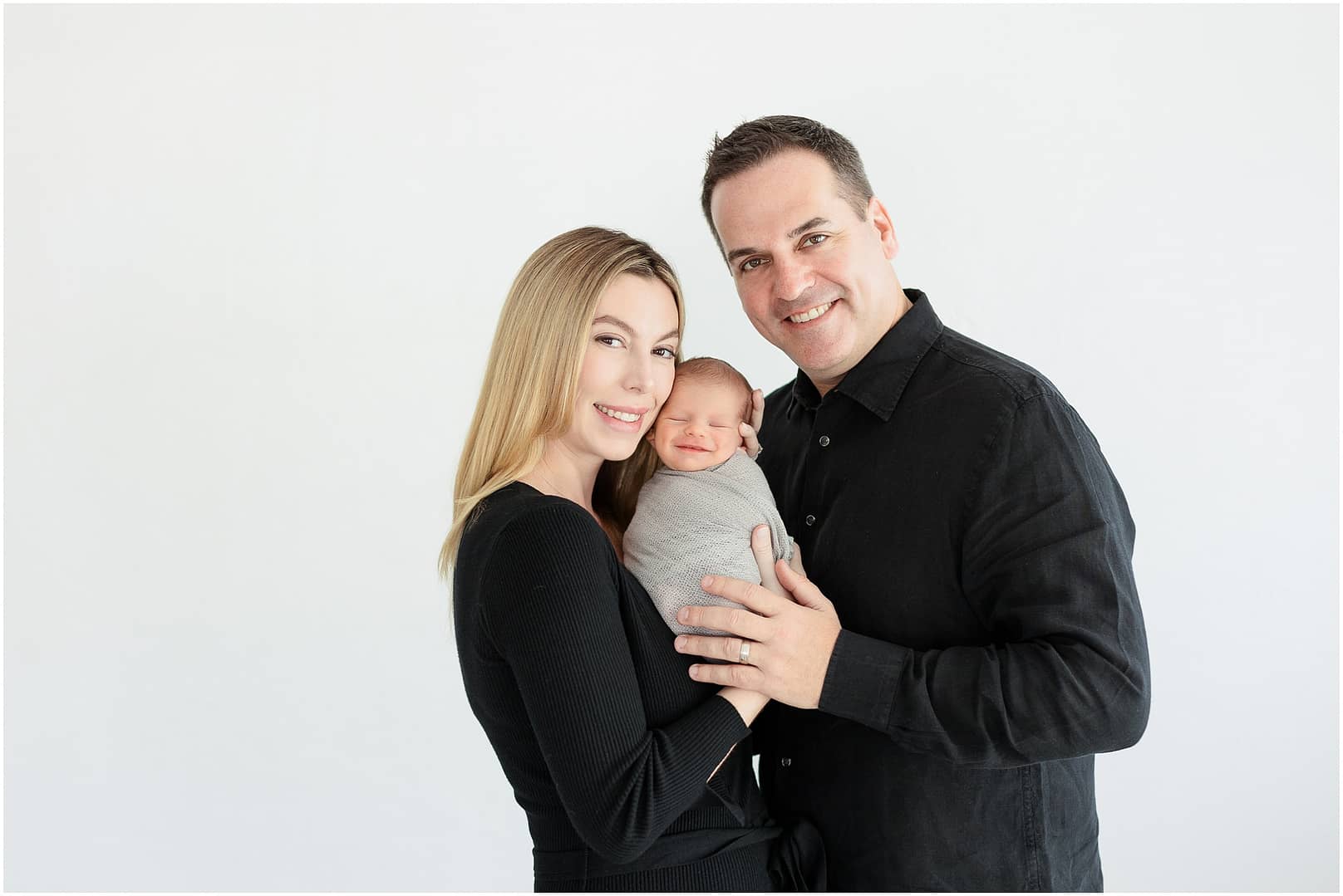 Baby boy smiles with his mom and dad during downtown Boise studio session. Photo by Tiffany Hix Photography.
