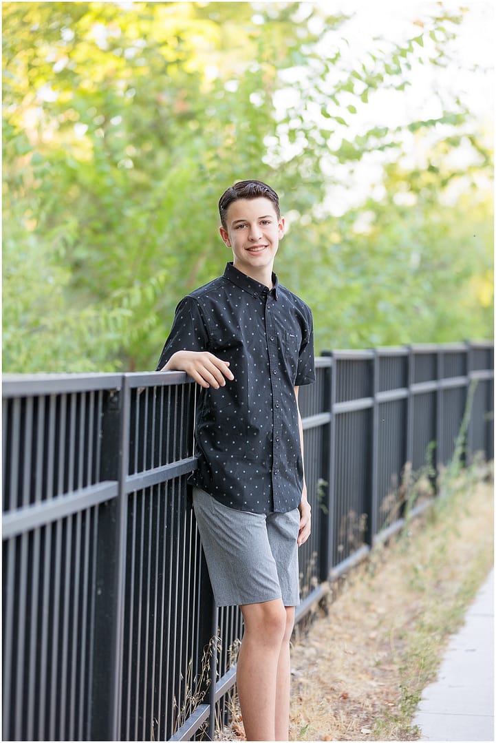 Teen boy casually leans against fence during tween portrait session. Photo by Tiffany Hix Photography.