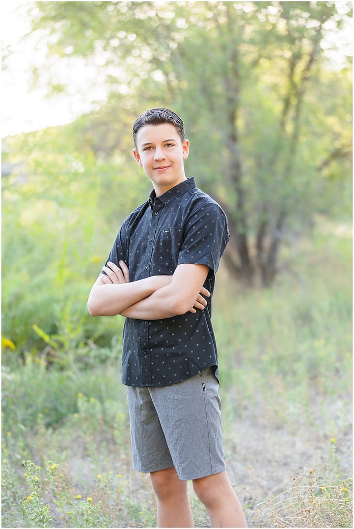 Teen by crossed his arms and close mouth smiles during Boise portrait session. Photo by Tiffany Hix Photography.