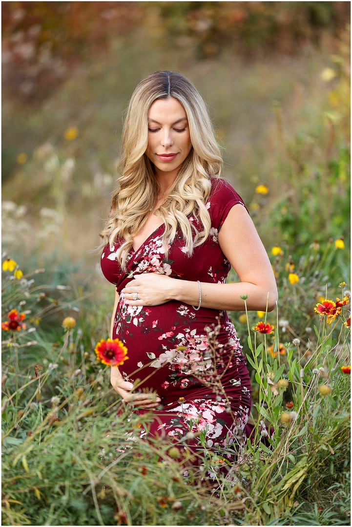 Mom holds her baby bump in field of Boise wildflowers. Photo by Tiffany Hix Photography.