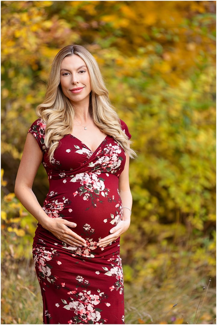 Pregnant mom stands among the beautiful fall foliage. Photo by Tiffany Hix Photography.