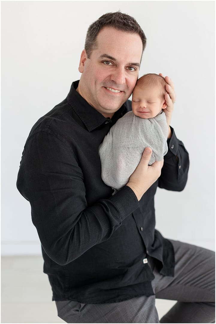 Dad proudly holds son during Boise newborn studio session. Photo by Tiffany Hix Photography.