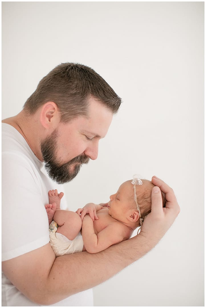 Dad holds baby on forearm. Photo by Tiffany Hix Photography.