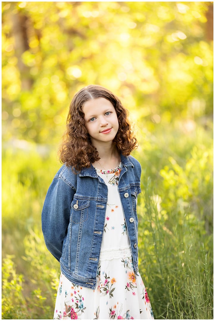 Teenage girl smiles while standing in green brush at Boise River. Photo by Tiffany Hix Photography.